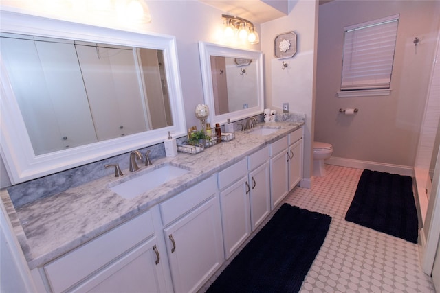 bathroom with double vanity, toilet, baseboards, and a sink