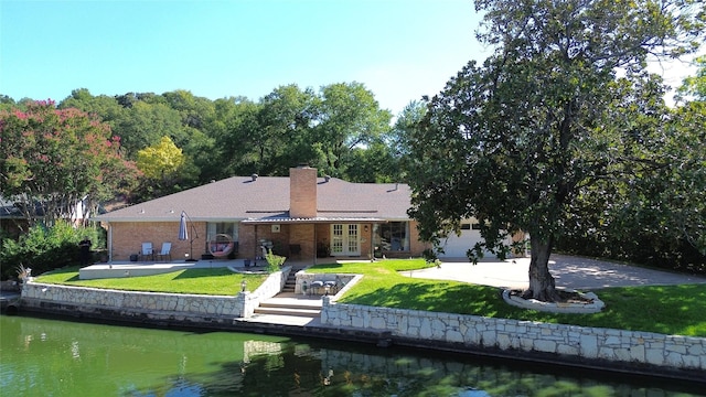 back of house featuring french doors, driveway, a yard, and a water view