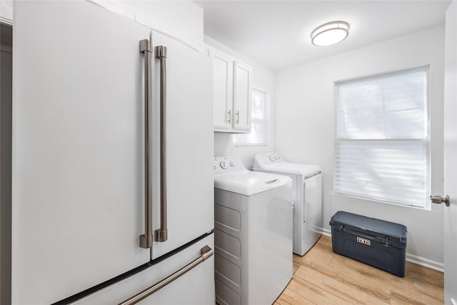 clothes washing area with baseboards, cabinet space, light wood-style flooring, and washing machine and clothes dryer