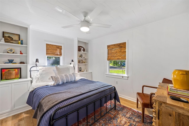 bedroom featuring ceiling fan, multiple windows, wood finished floors, and ornamental molding