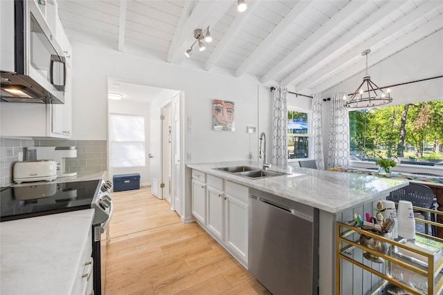 kitchen with light wood finished floors, a sink, decorative backsplash, appliances with stainless steel finishes, and white cabinetry