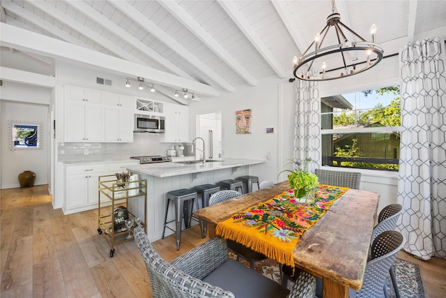 dining area featuring visible vents, lofted ceiling with beams, wooden ceiling, light wood finished floors, and a chandelier