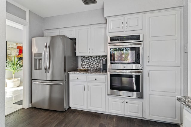 kitchen featuring light stone countertops, visible vents, dark wood-type flooring, white cabinets, and appliances with stainless steel finishes