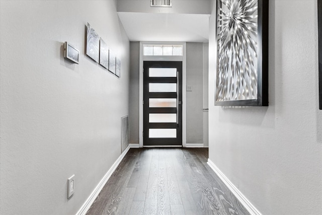 foyer entrance featuring dark wood-type flooring, baseboards, and visible vents