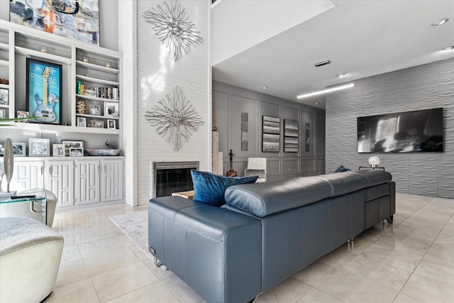 living room featuring tile patterned floors, built in shelves, a brick fireplace, and an accent wall