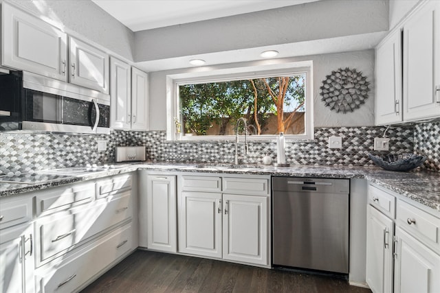 kitchen with a sink, dark wood-type flooring, appliances with stainless steel finishes, white cabinetry, and tasteful backsplash