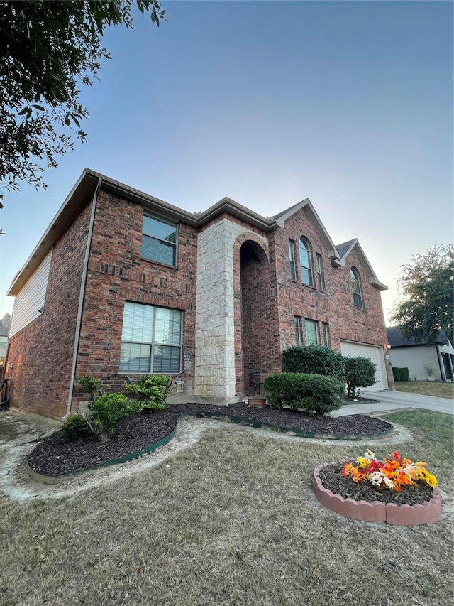 traditional home featuring a garage, brick siding, and driveway