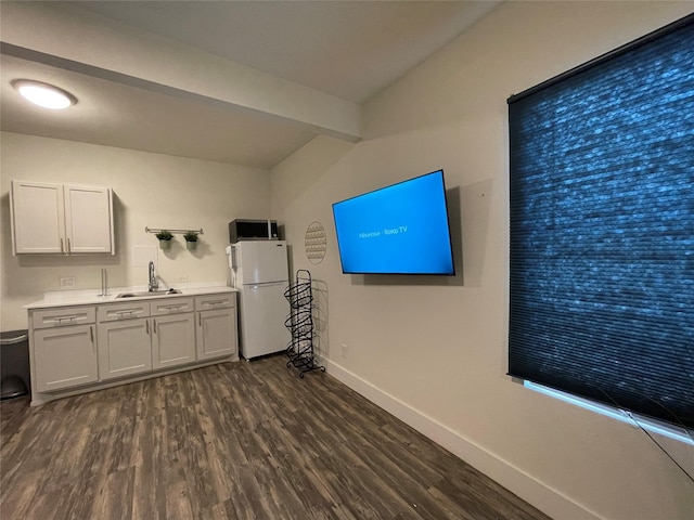 interior space with baseboards, dark wood-style flooring, freestanding refrigerator, a sink, and light countertops