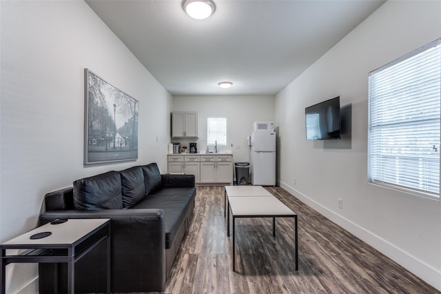 living area with dark wood-type flooring and baseboards