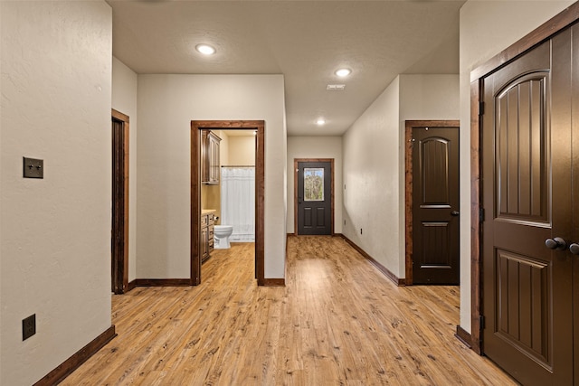 hallway featuring baseboards and light wood-style floors