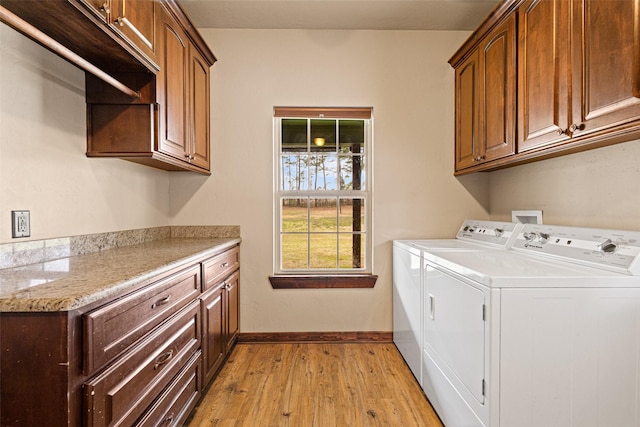 laundry area with baseboards, light wood-type flooring, cabinet space, and independent washer and dryer