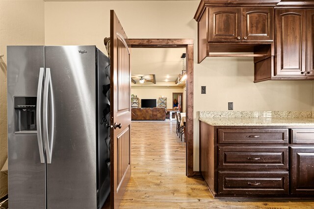 kitchen featuring dark brown cabinetry, light wood-style floors, stainless steel refrigerator with ice dispenser, and light stone countertops