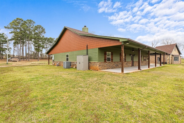 view of property exterior with cooling unit, a yard, a chimney, stone siding, and a patio area