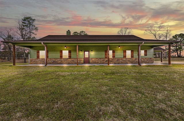 exterior space with a yard, stone siding, covered porch, and a chimney