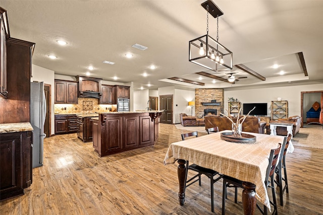 dining area with visible vents, a fireplace, ceiling fan, a textured ceiling, and light wood-type flooring