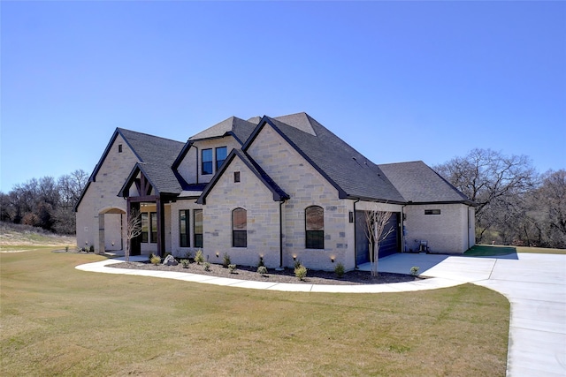 view of front of property with a shingled roof, a front yard, a garage, stone siding, and driveway