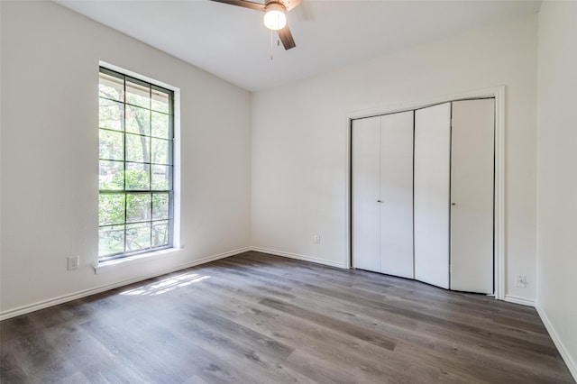 unfurnished bedroom featuring a closet, baseboards, wood finished floors, and a ceiling fan