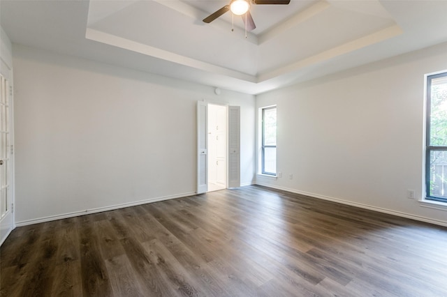 unfurnished room with dark wood-type flooring and a tray ceiling