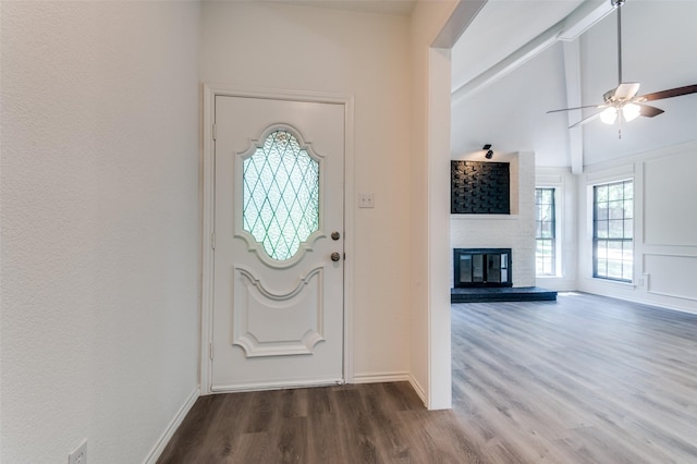 entrance foyer with baseboards, a large fireplace, wood finished floors, and vaulted ceiling with beams