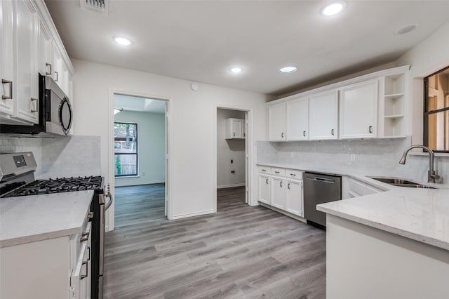 kitchen featuring light wood-style flooring, a sink, open shelves, stainless steel appliances, and white cabinets