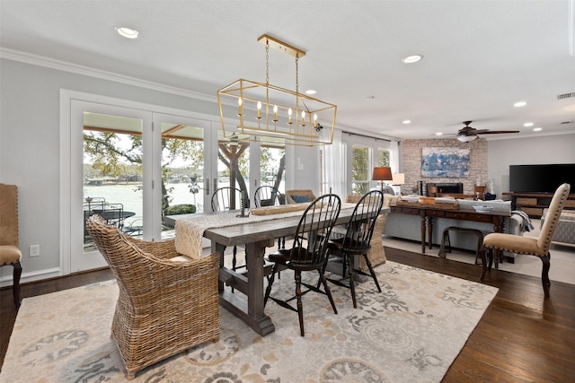 dining area with a large fireplace, recessed lighting, wood finished floors, and ornamental molding