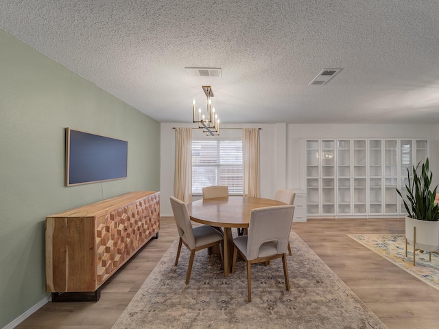 dining space with visible vents, a notable chandelier, and wood finished floors