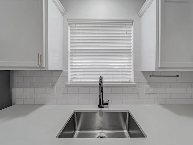 kitchen featuring a sink, tasteful backsplash, white cabinets, and light countertops