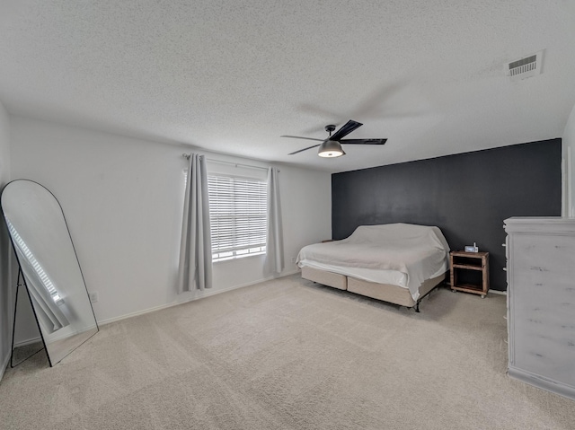 carpeted bedroom featuring a textured ceiling, baseboards, visible vents, and ceiling fan