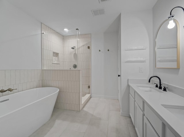 bathroom featuring visible vents, double vanity, a stall shower, a freestanding tub, and a sink