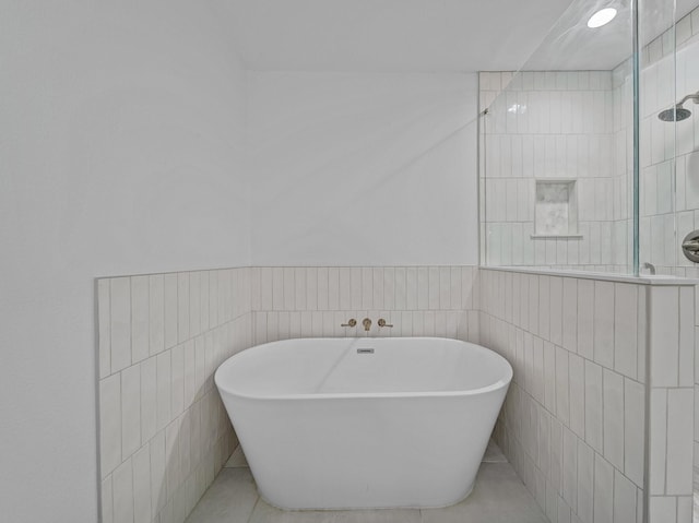 full bath featuring tiled shower, a freestanding bath, tile walls, and a wainscoted wall