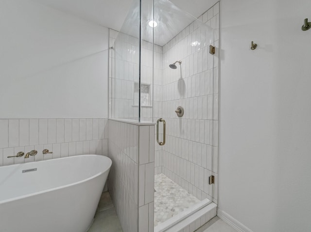 full bath with a freestanding tub, tile walls, and a stall shower