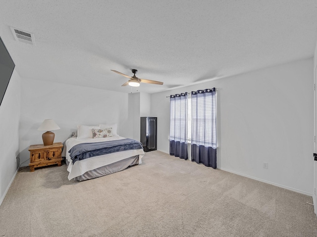 carpeted bedroom with baseboards, visible vents, a textured ceiling, and a ceiling fan