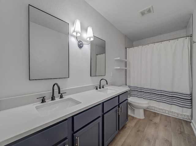 bathroom featuring visible vents, toilet, wood finished floors, and a sink