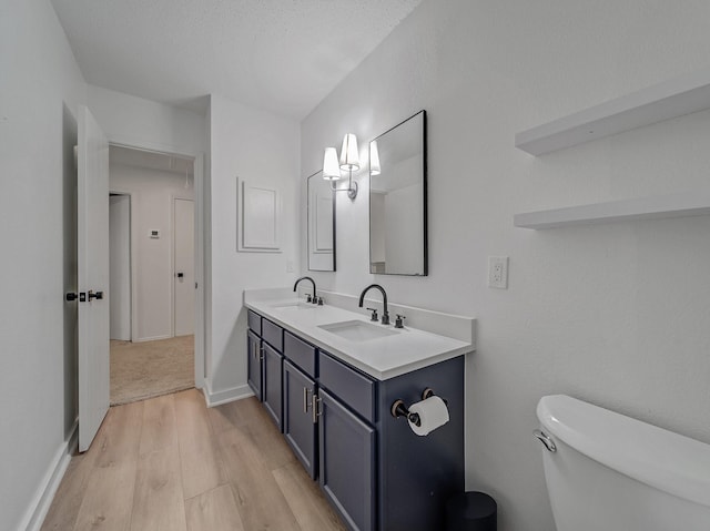 bathroom featuring a sink, toilet, wood finished floors, and double vanity