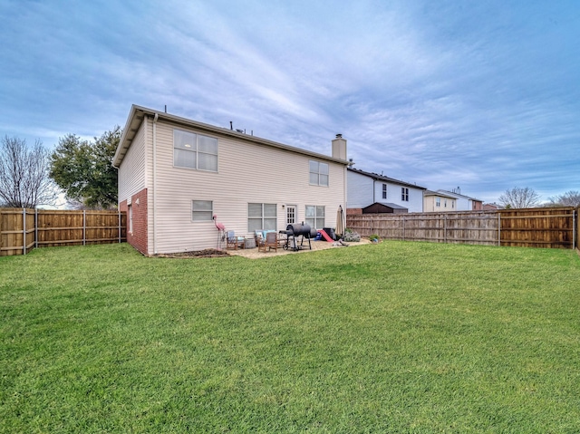 back of house featuring a lawn, a fenced backyard, and a chimney