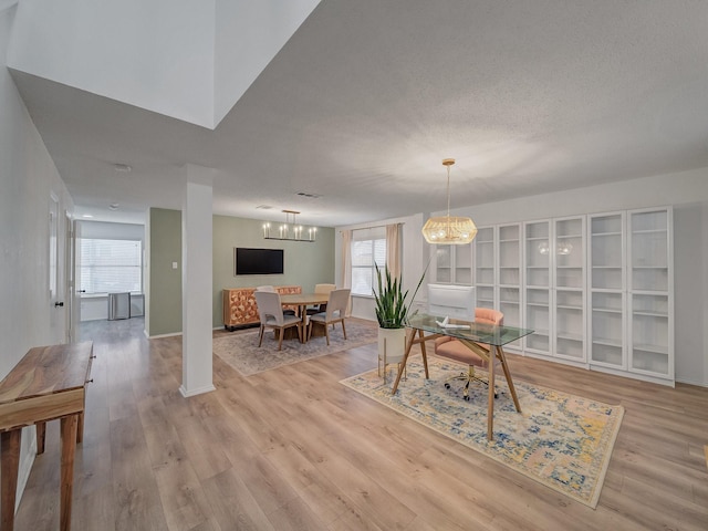 dining area featuring baseboards, light wood-style floors, a chandelier, and a textured ceiling