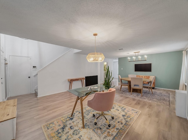 dining area featuring a textured ceiling, stairs, and light wood-style floors