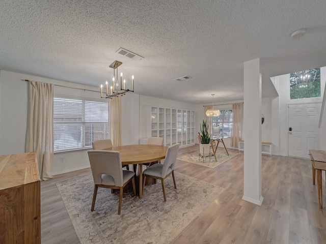 dining space with a notable chandelier, visible vents, and light wood-type flooring