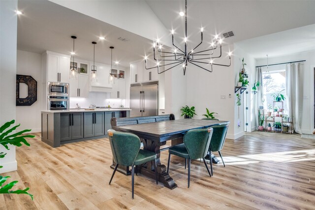 dining area featuring light wood finished floors, visible vents, and baseboards