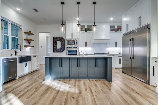 kitchen featuring visible vents, built in appliances, light countertops, custom exhaust hood, and a sink