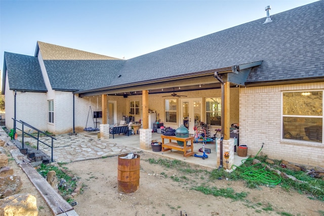 rear view of house featuring brick siding, french doors, a shingled roof, and a patio