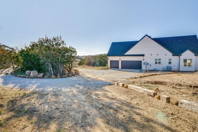 view of side of property with gravel driveway and cooling unit