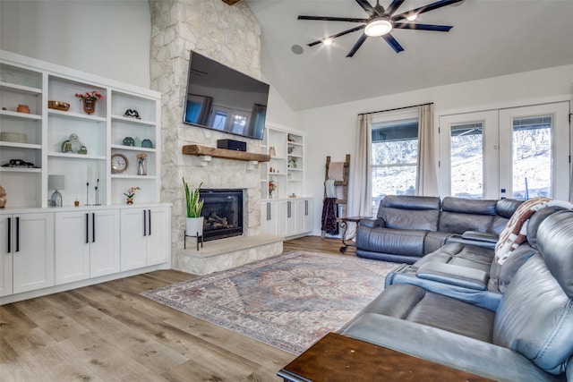 living room with a stone fireplace, a healthy amount of sunlight, and light wood finished floors