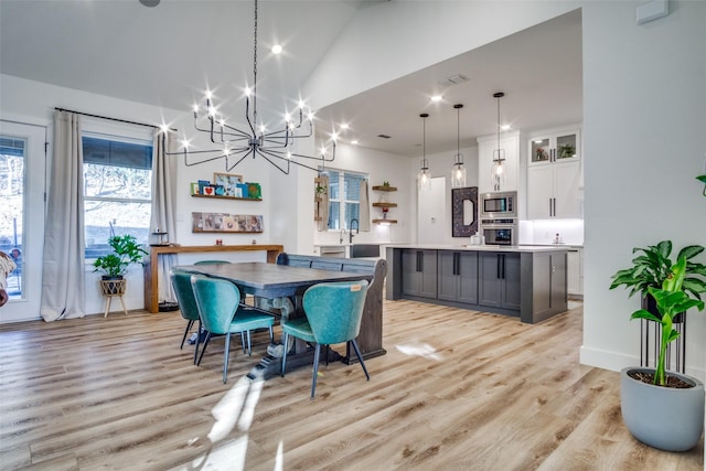 dining room with lofted ceiling, light wood-style flooring, and visible vents