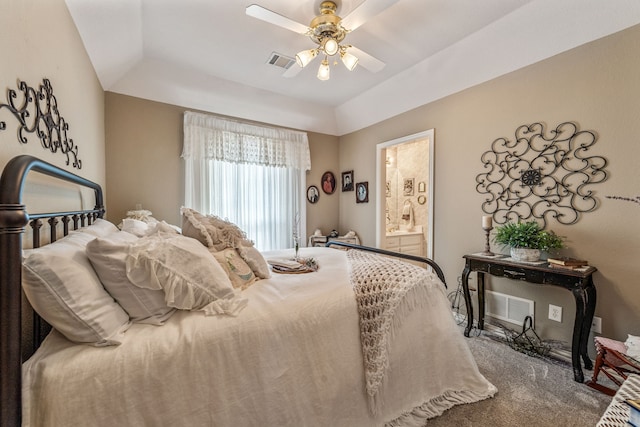 carpeted bedroom with visible vents, ensuite bath, a tray ceiling, and ceiling fan