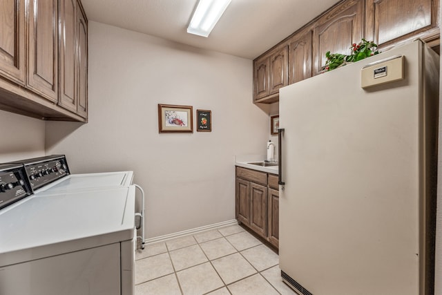 clothes washing area with light tile patterned floors, baseboards, cabinet space, a sink, and independent washer and dryer