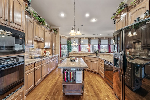 kitchen featuring black appliances, a peninsula, backsplash, and a sink