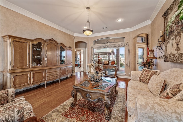 living room featuring visible vents, arched walkways, wood finished floors, and crown molding