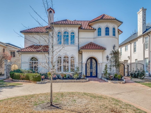 mediterranean / spanish home featuring stucco siding, french doors, and a tile roof