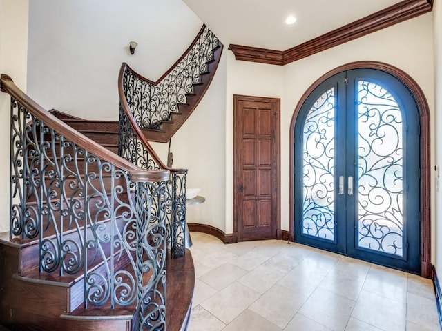 tiled entryway with baseboards, french doors, arched walkways, and ornamental molding